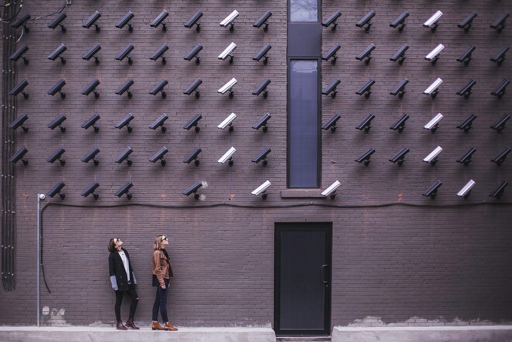 A wall of security cameras watching two people below